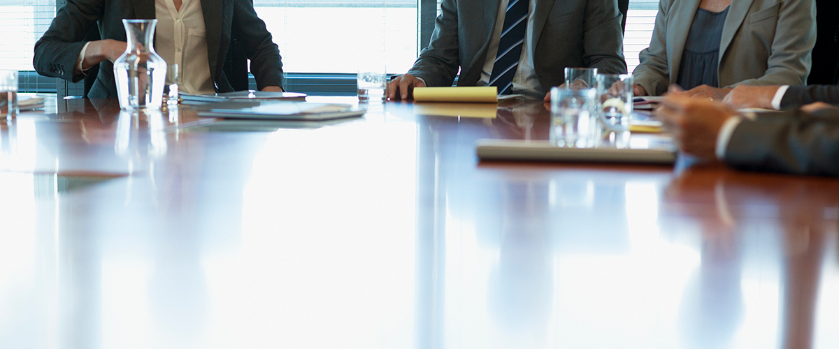 An image of executives sitting around a board room table.