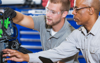 An image of two men working on mechanical equipment.