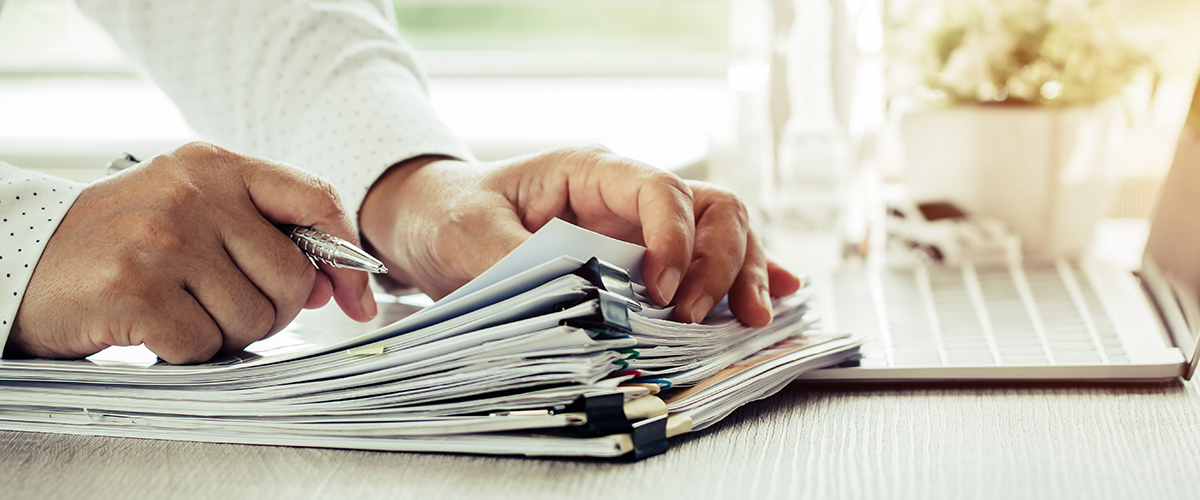 An image of an employee reviewing a stack of files.