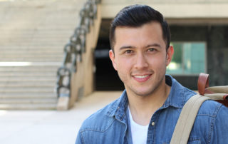 An image of a young man standing outside a school building.