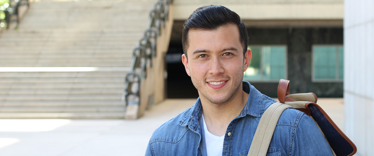 An image of a young man standing outside a school building.